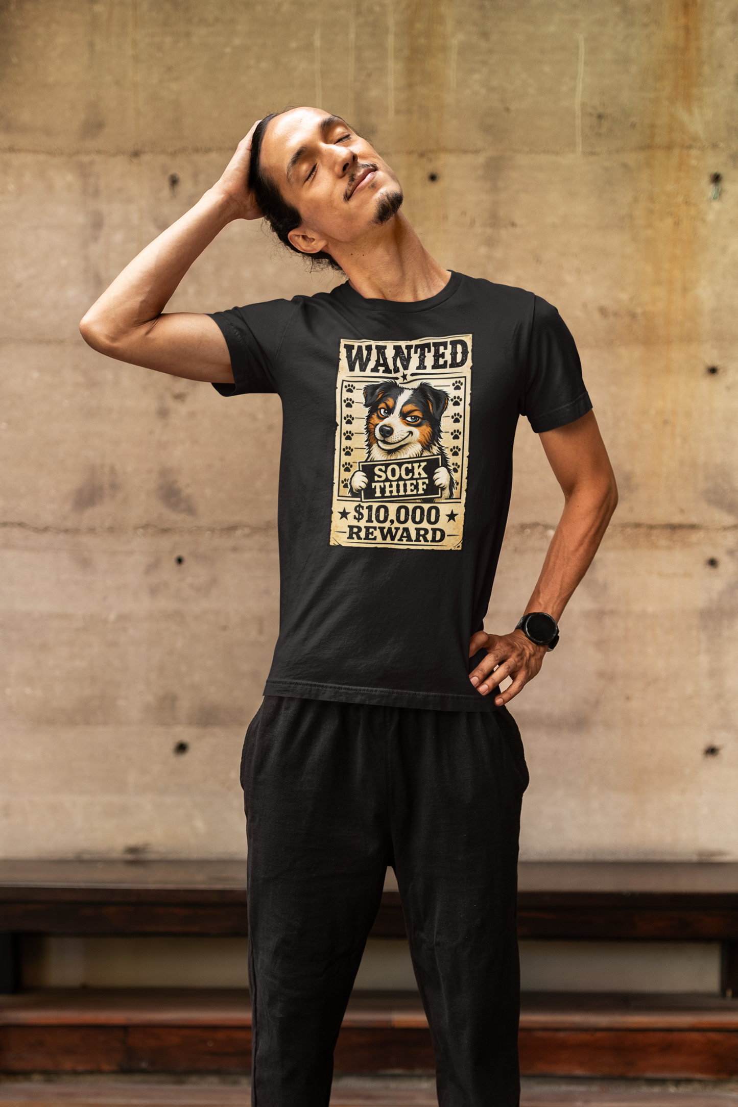 Man wearing a black t-shirt with a graphic design of a dog and text, standing against a concrete wall.