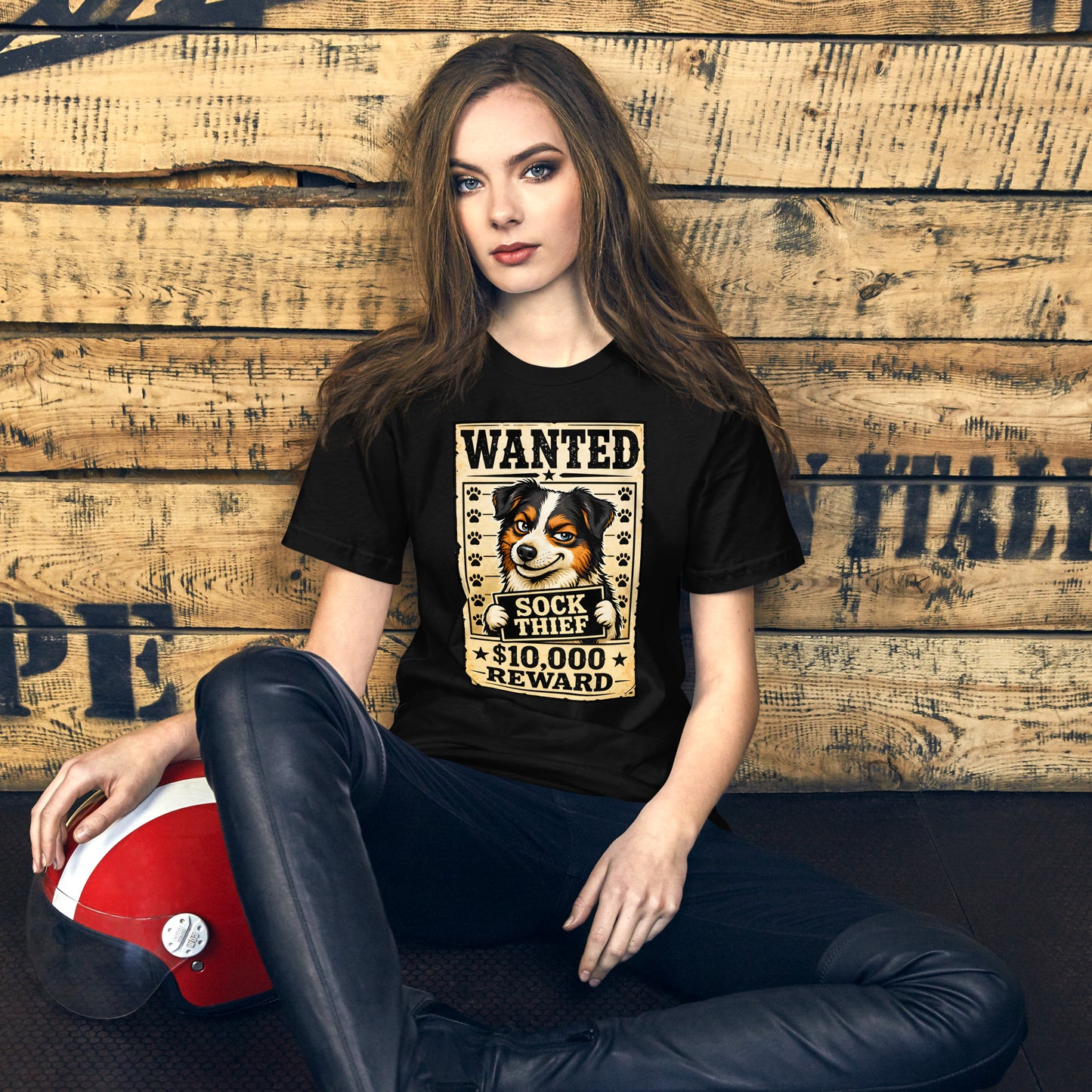 Woman wearing a black t-shirt with a dog graphic and text, sitting against a wooden wall.